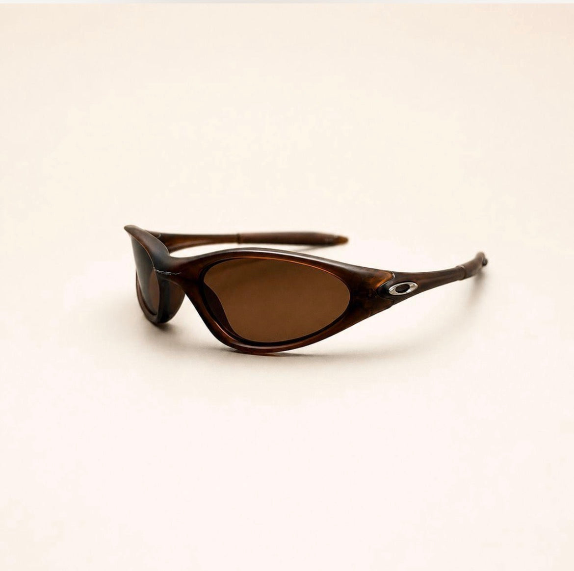 Oakley Minute brown sunglasses with brown lenses and silver oval temple details, three-quarter view.