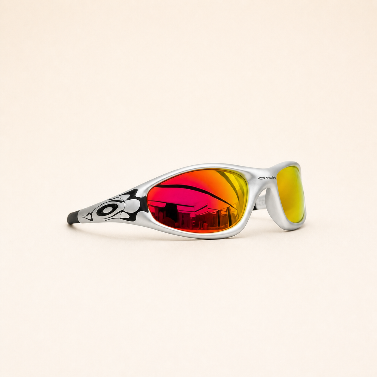 Oakley Minute sunglasses in silver with black flame graphics and red-orange mirrored lenses, three-quarter view.